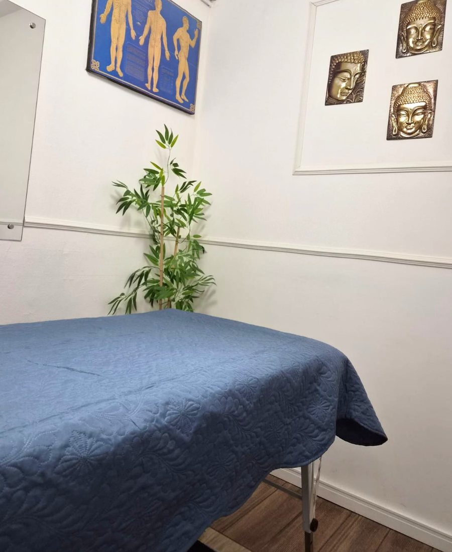 Sala de atendimento com maca e mapa de meridianos